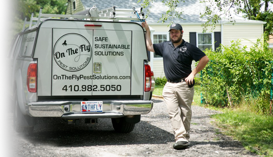 An image of a man standing in a driveway outside one of the On The Fly Pest Solutions trucks.