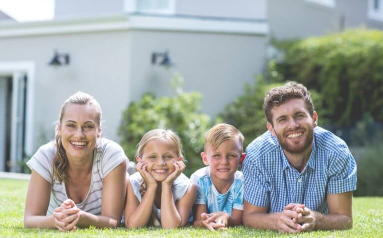 An image of a family laying in the grass, smiling.